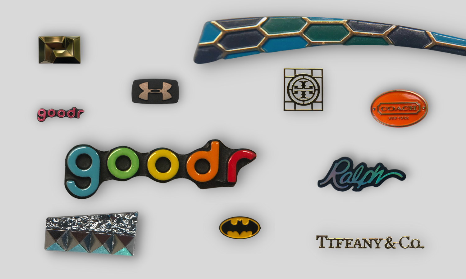 collage of small badges for eyewear: rainbow colored goodr; trans pink goodr; batman symbol, crushed glass/pyramid chrome, tiffany gold letters; tory burch gold letters, coach oval badge with orange background and gold copy, ralph script logo with black background and raised hologram copy, under armour square with black background and raw steel copy, mosaic trim piece with gold bridging and blue and green pieces